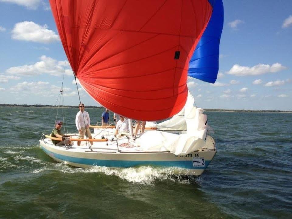 Auxiliary fleet keelboat flying a red and blue spinnaker on Lake Ray Hubbard