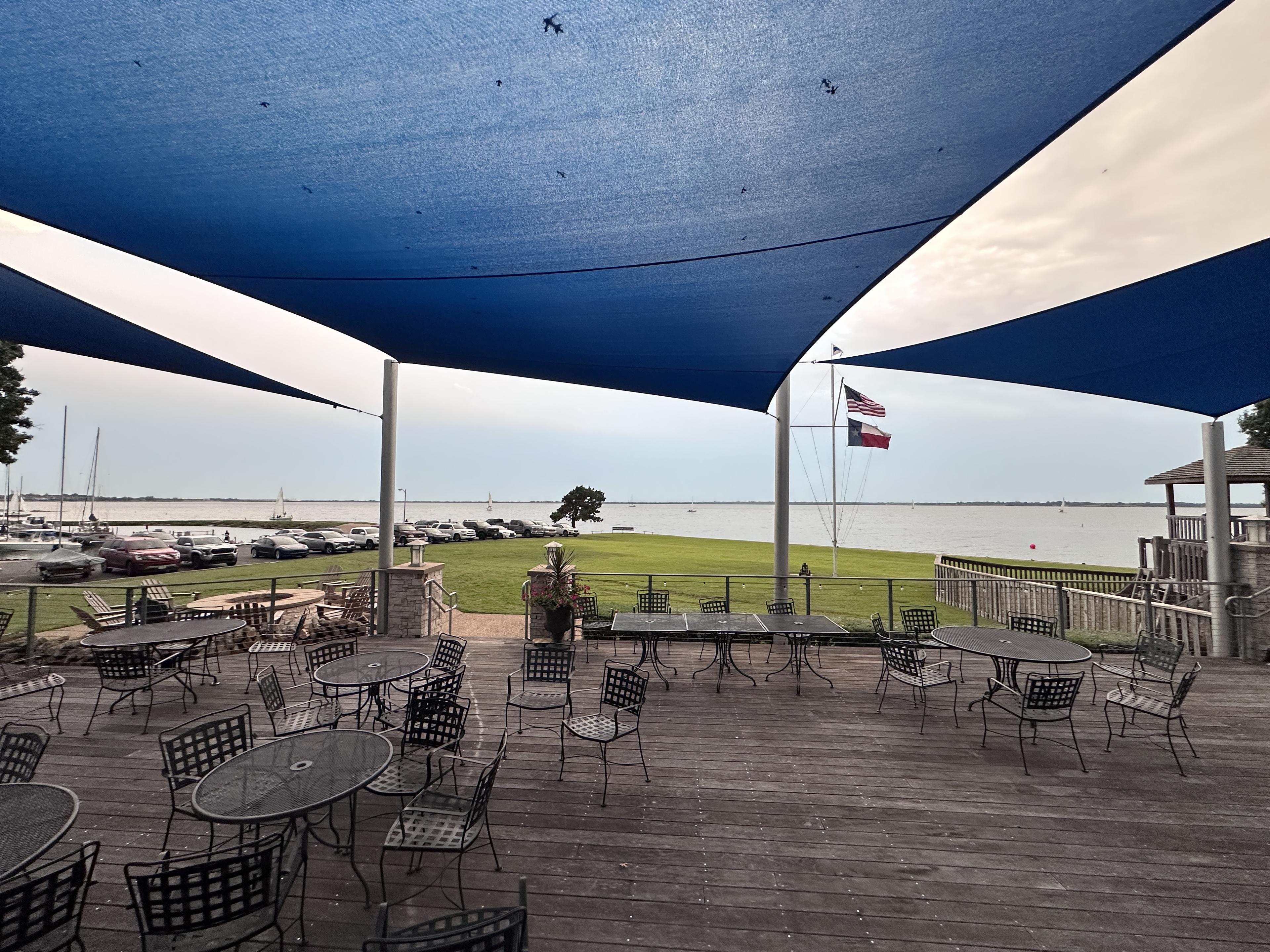 Rush Creek Yacht Club deck with blue shade sails and marina view