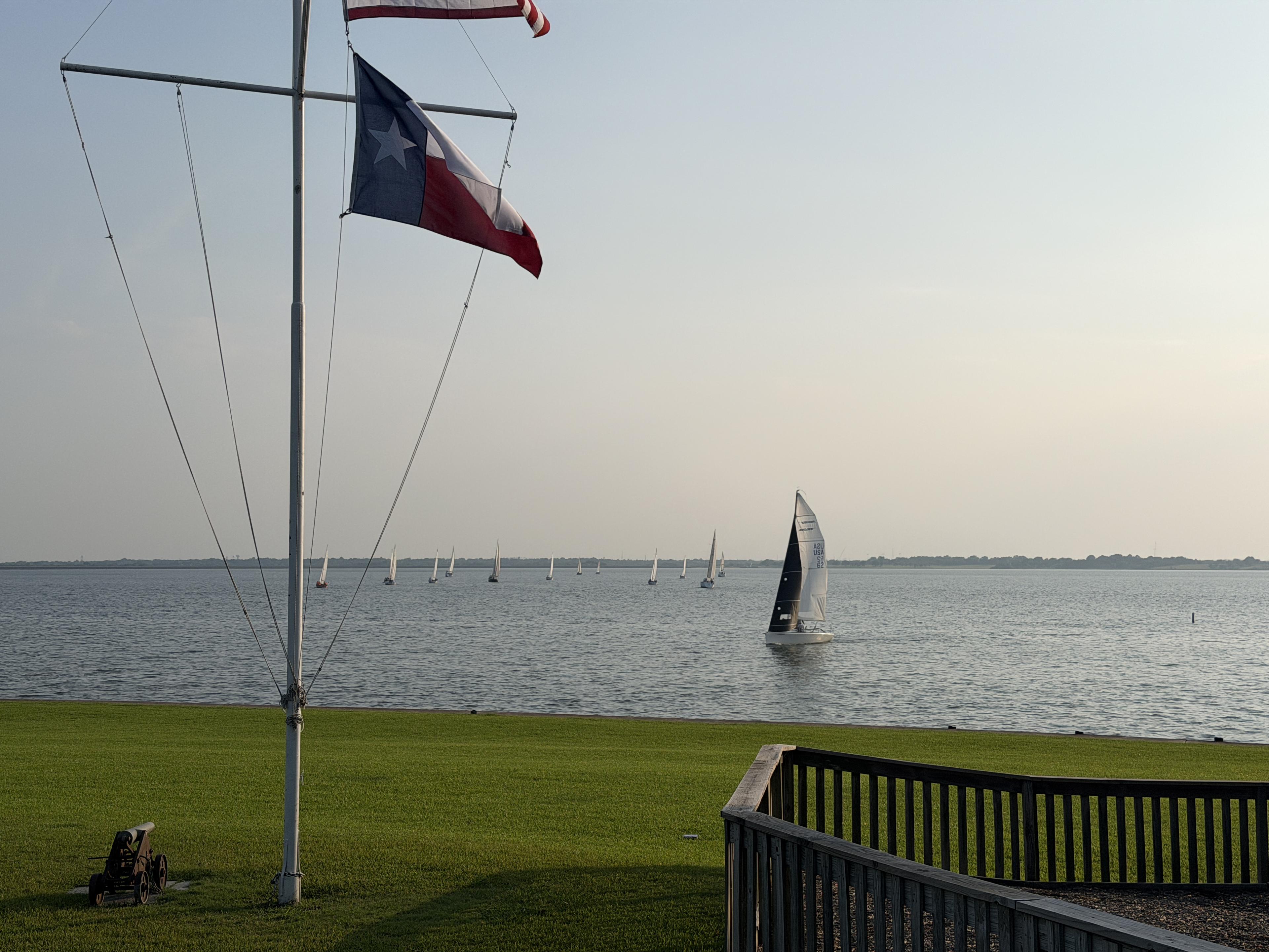 Texas flag flying over the Rush Creek Yacht Club with racing fleet on Lake Ray Hubbard