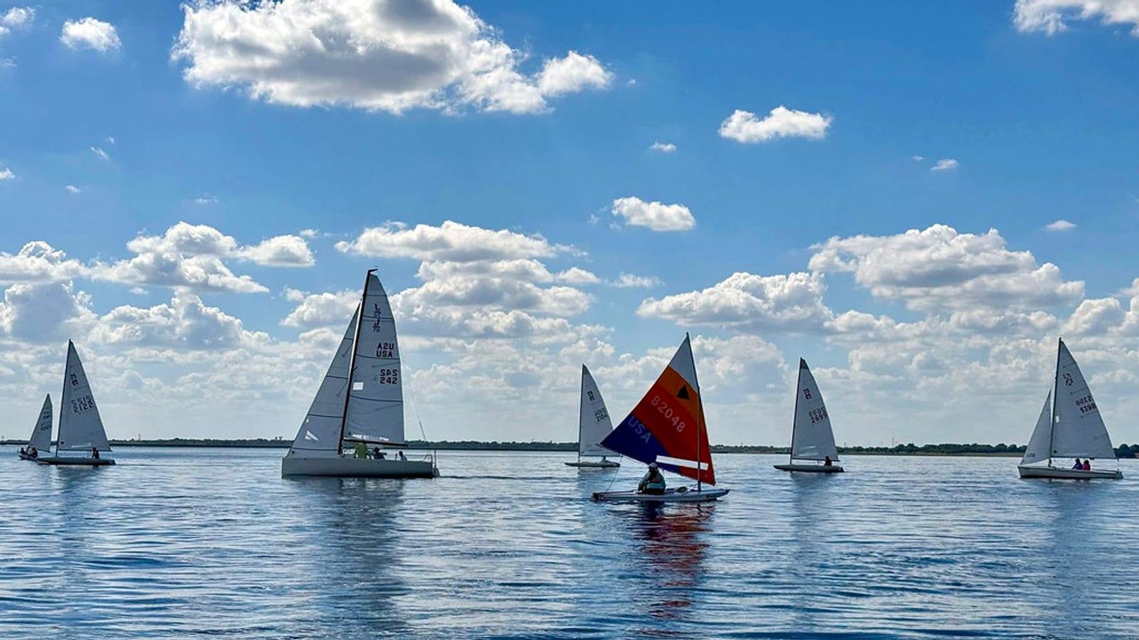 Sailboats racing on calm water under a wide sky at Rush Creek