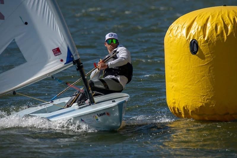 ILCA sailor rounding a yellow inflatable mark in close racing action