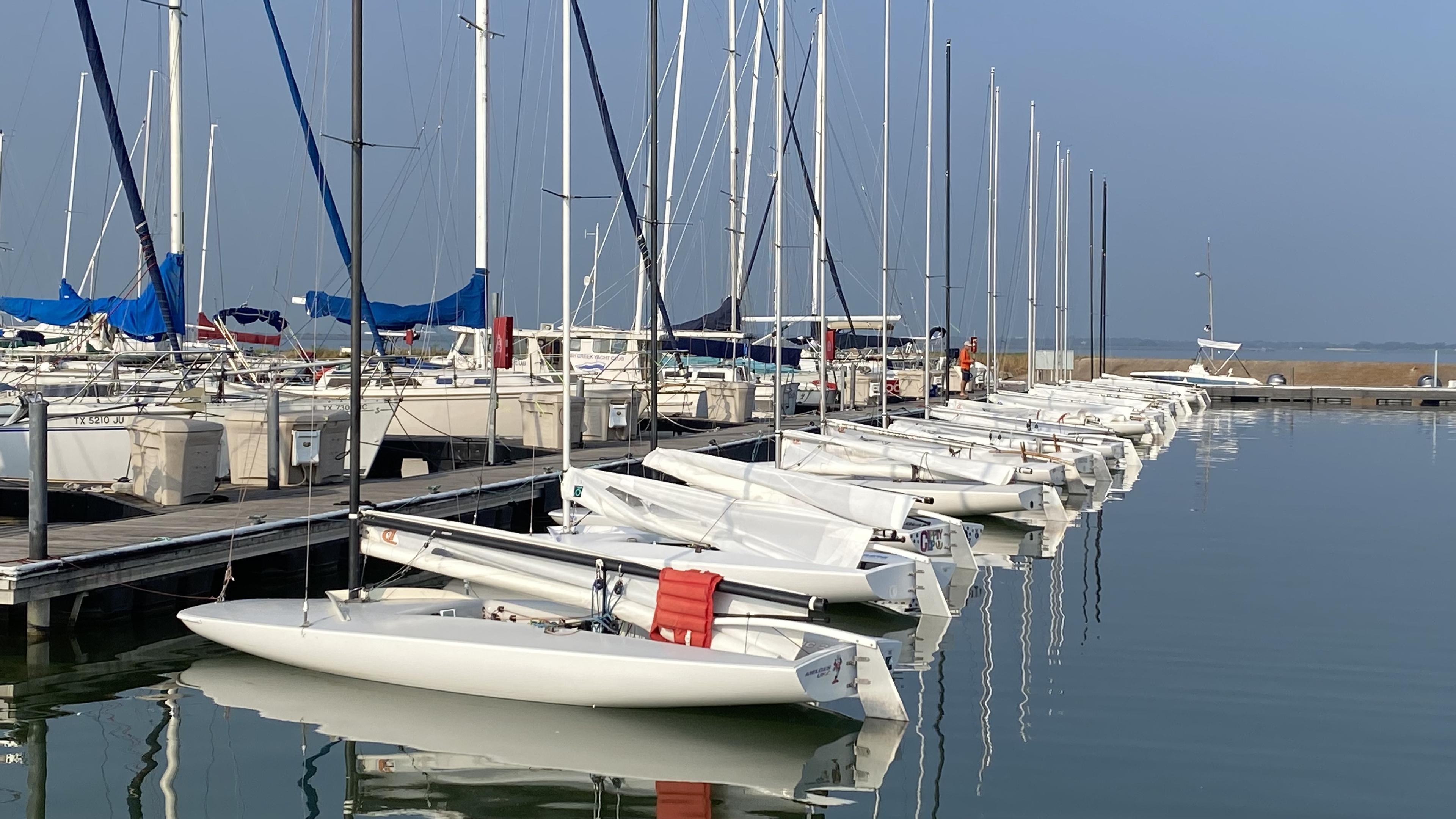 MC Scow fleet moored at the Rush Creek Yacht Club dock on a calm morning