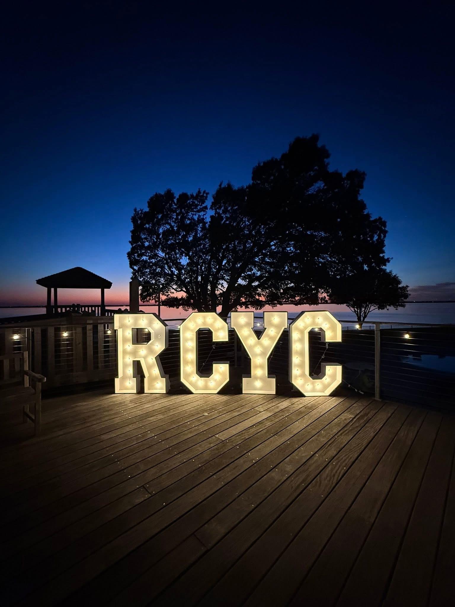 Illuminated RCYC marquee letters on the club deck at dusk