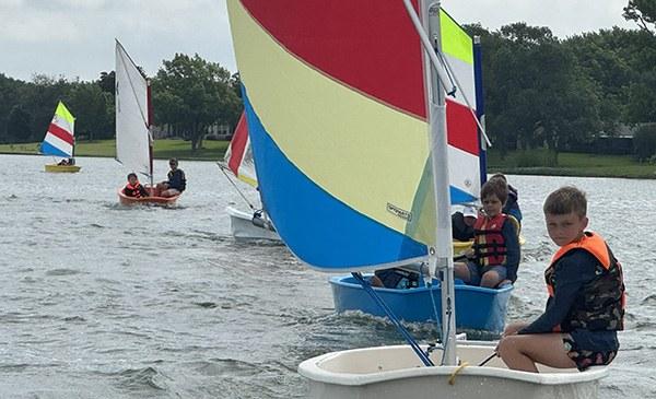 Youth sailors in colorful Optimist dinghies during Rush Creek sailing camp